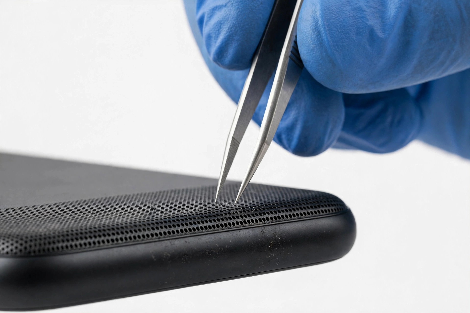 Technician inspecting phone speaker grille with tweezers