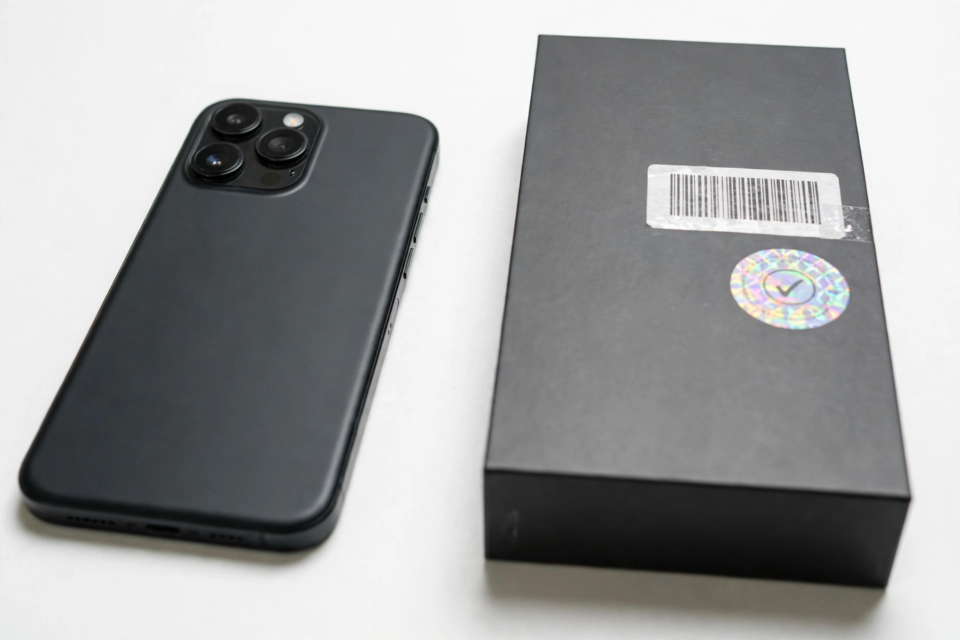Smartphone next to retail box with barcode and serial number verification labels